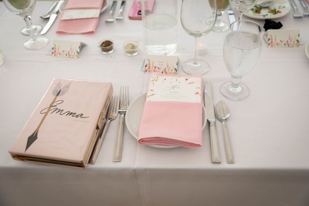 Elegant table settings with pink napkins and menus arranged on a white tablecloth for a formal dining event.