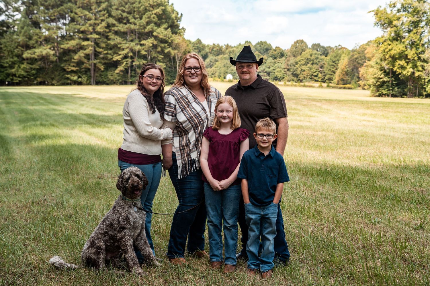 Group poses together in a grassy field on a sunny autumn day.