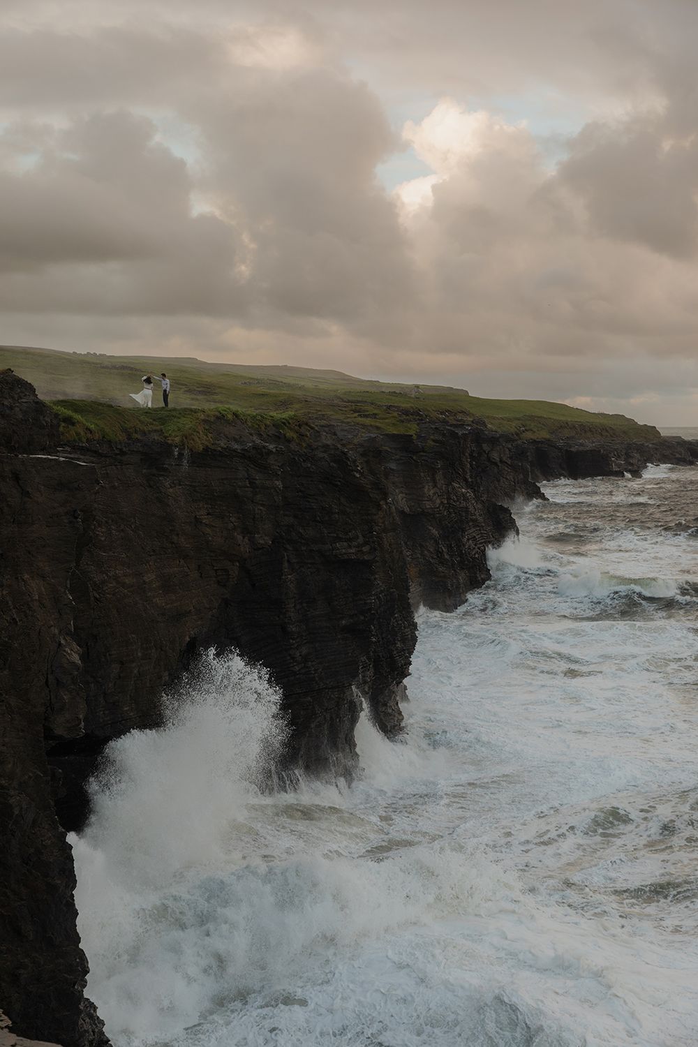 Elopement couple walking along Cliffs of Moher coastline at sunrise