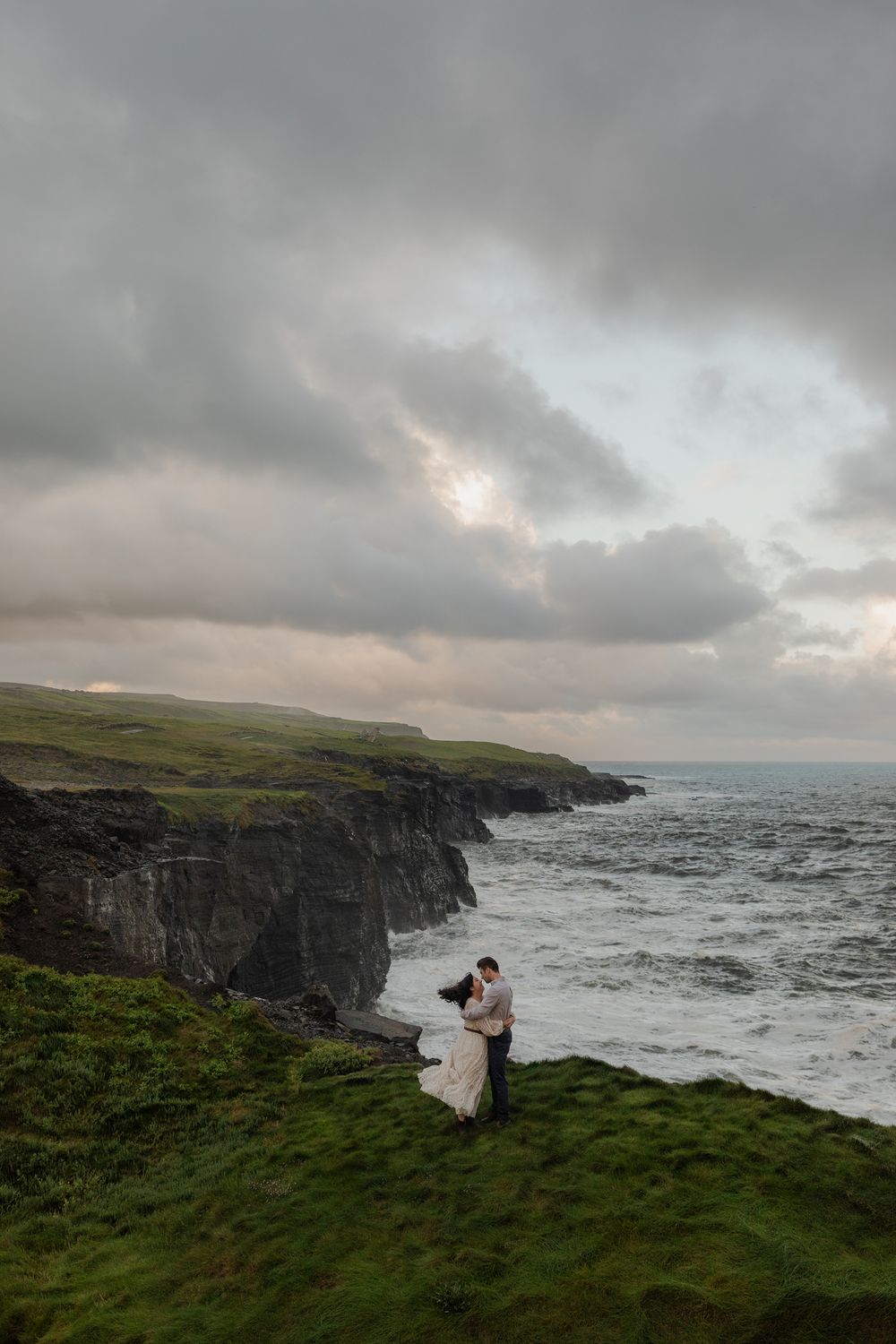 Couple embracing on Cliffs of Moher during sunrise adventure session