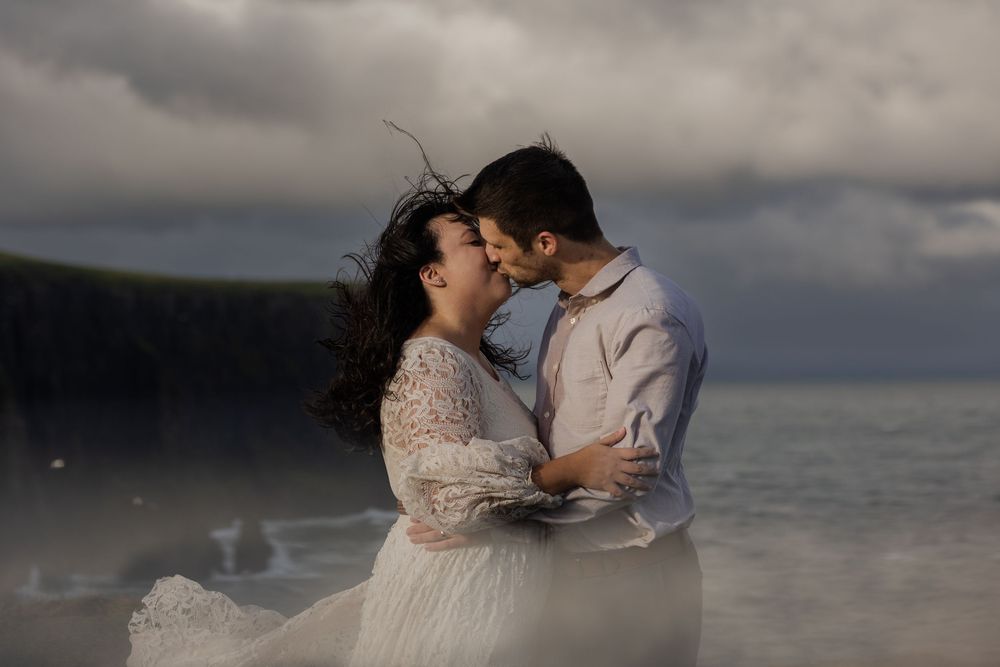 Bride and groom standing near Cliffs of Moher during sunrise elopement