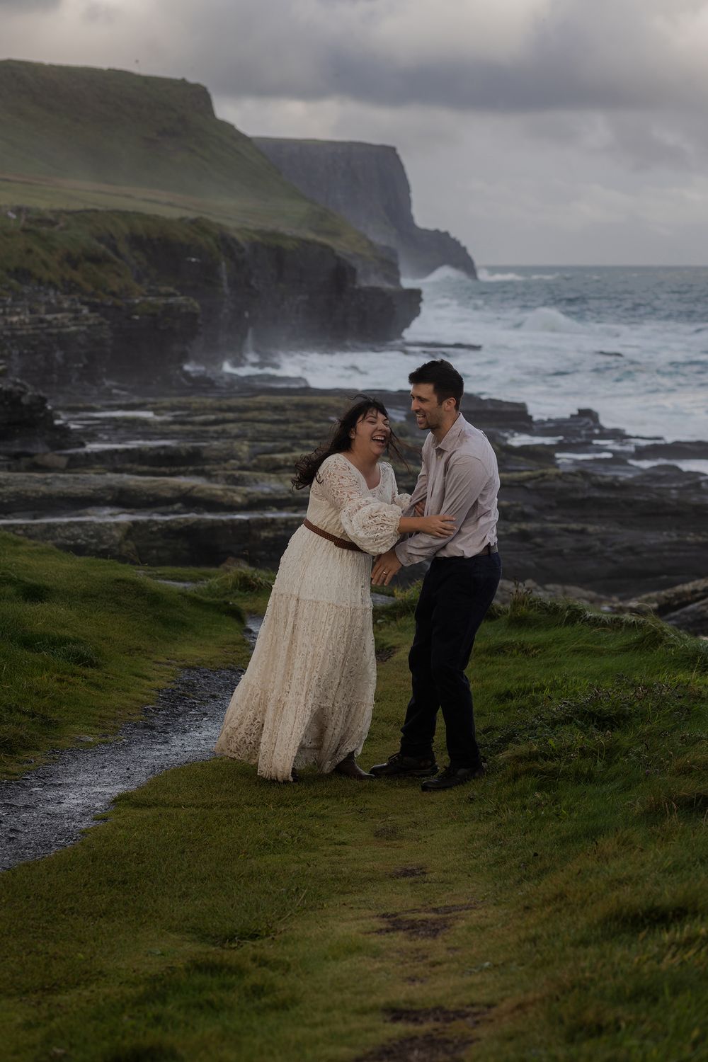 Couple hiking along Cliffs of Moher trail during sunrise couples session