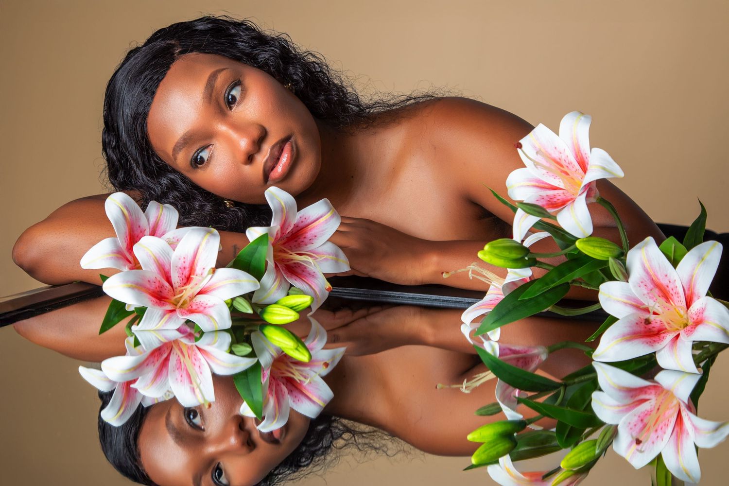 A person poses with pink and white lilies in a creative portrait series against a neutral background.