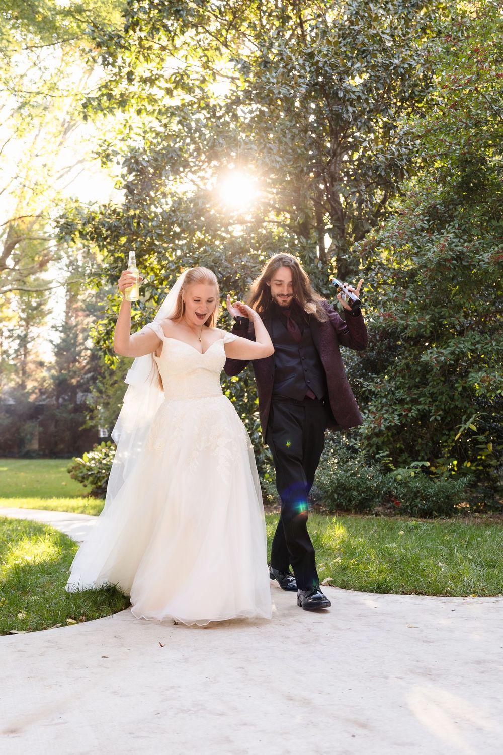 Bride in white dress twirls and dances joyfully in sunlit outdoor setting.