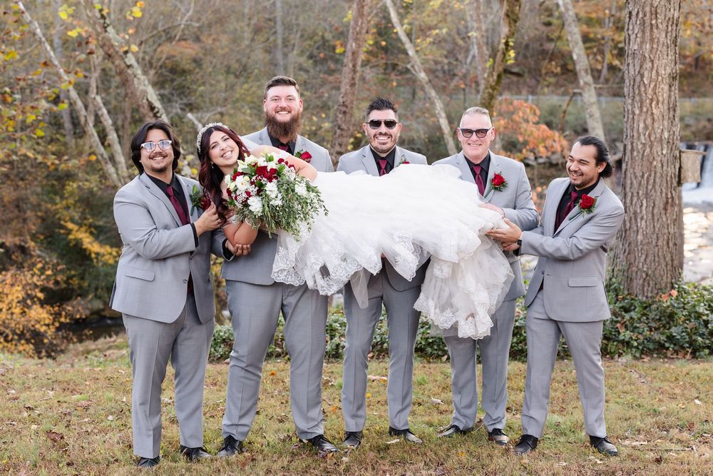 Groomsmen in gray suits pose playfully together during outdoor autumn wedding photoshoot.