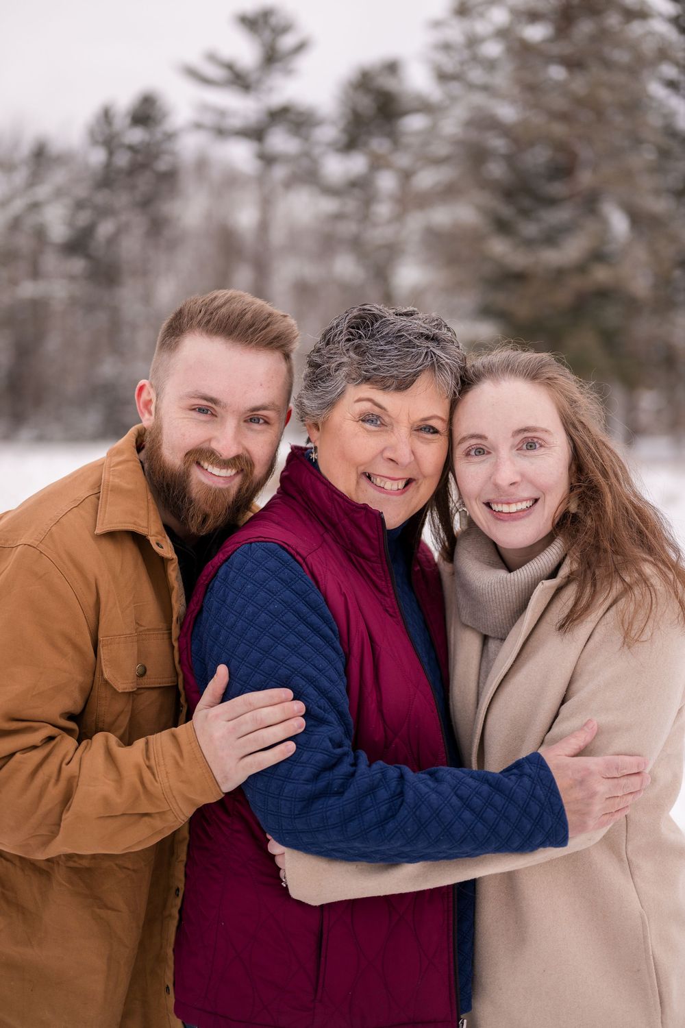 Happy family embracing during winter photo session in snowy landscape.