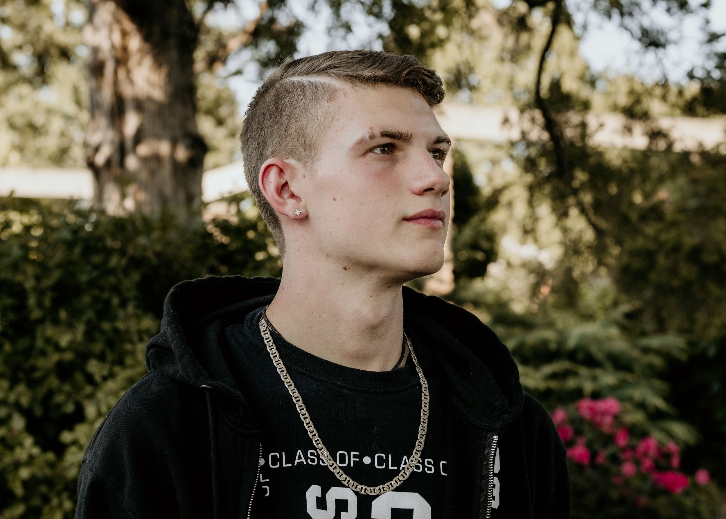 A high school senior poses outdoors at sunset.