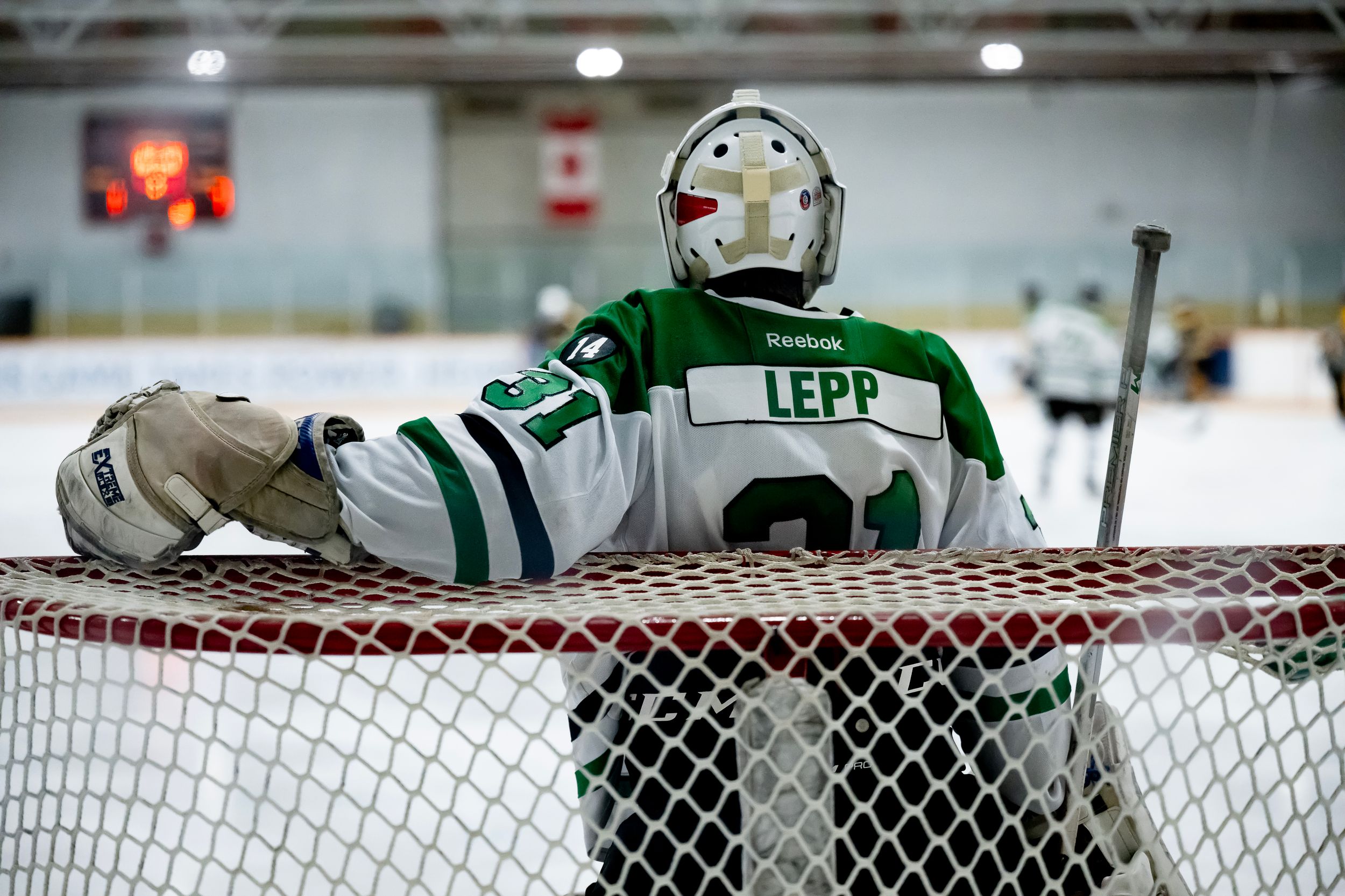 A hockey goalie stretches across the goal crease to make a save during an ice hockey game.