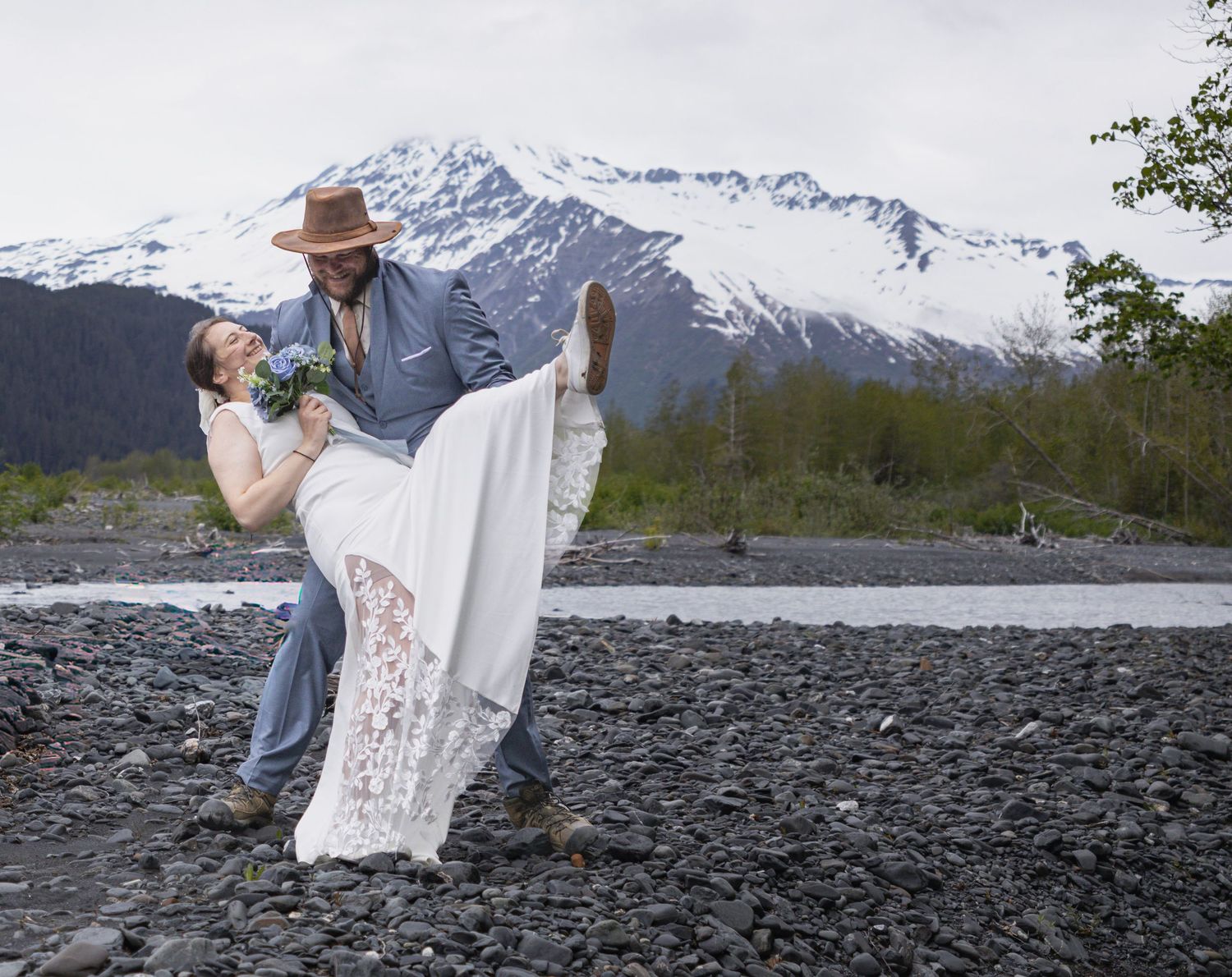 A couple shares an intimate moment together in a snowy winter field on a cloudy day.