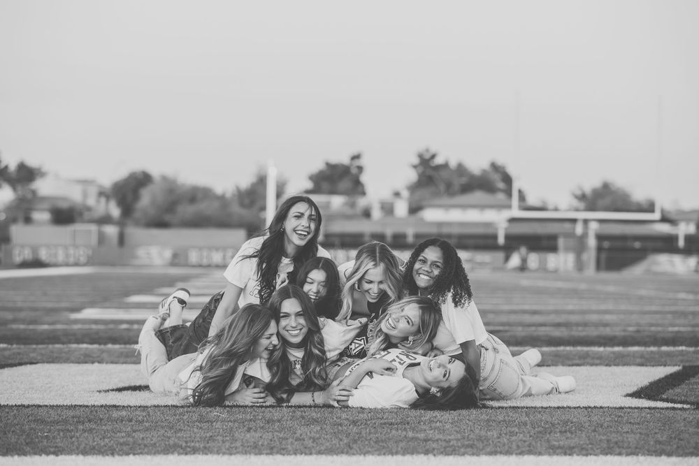 A group sits together on a blanket outdoors in a black and white photograph.