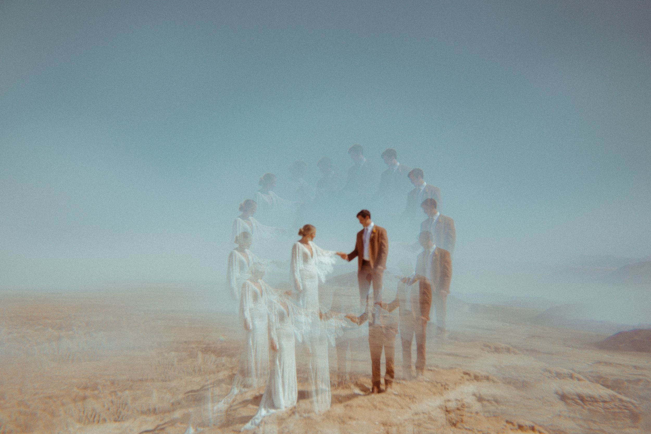 A group of people stand in a row on a misty beach at sunset, creating a dreamy silhouette effect.
