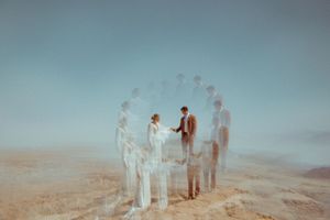 A group of people stand in a row on a misty beach at sunset, creating a dreamy silhouette effect.