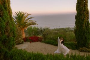 A scenic coastal wedding venue at sunset with cypress trees, palm trees and ocean views in the background.