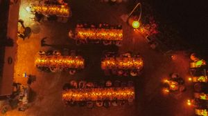 Glowing orange lanterns illuminate a dark pathway through trees creating a warm and magical nighttime atmosphere.