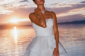 A sunset beach wedding photoshoot with someone in a white dress posing against the colorful sky and ocean backdrop.