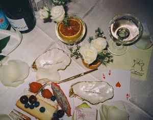 Overhead view of oysters, playing cards, cocktails and appetizers on a white tablecloth at an elegant dinner setting.