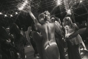 A crowd of people dance and celebrate at a nightclub with dramatic lighting and sparklers overhead.
