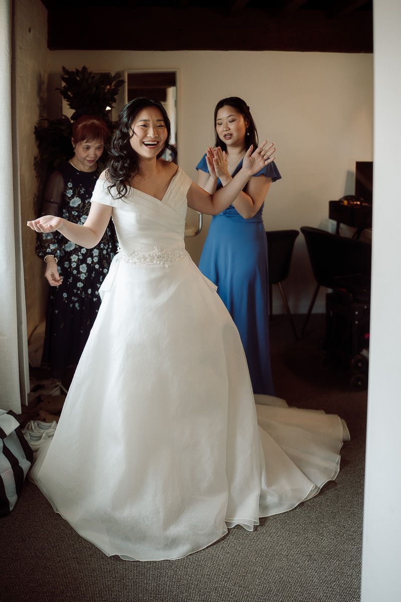 Wedding party gathers around bride in elegant white ballgown as they prepare for the ceremony.