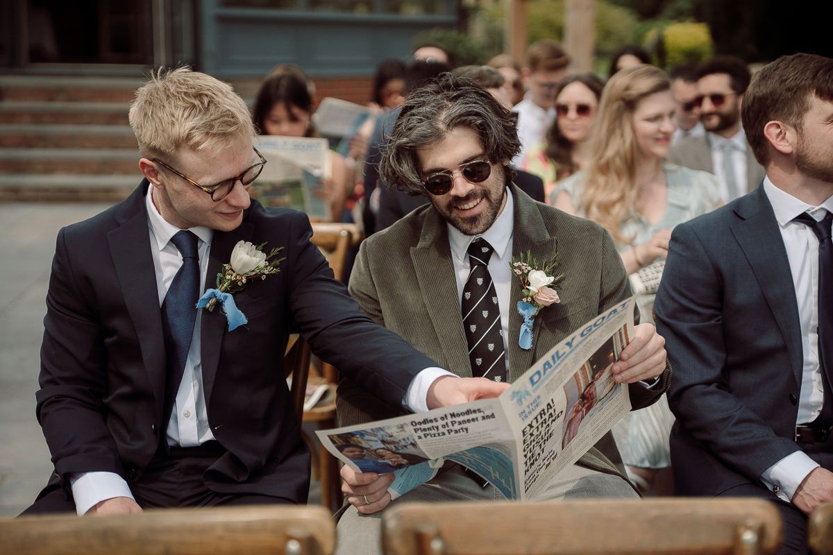 Wedding guests seated outdoors in formal attire watching ceremony proceedings.
