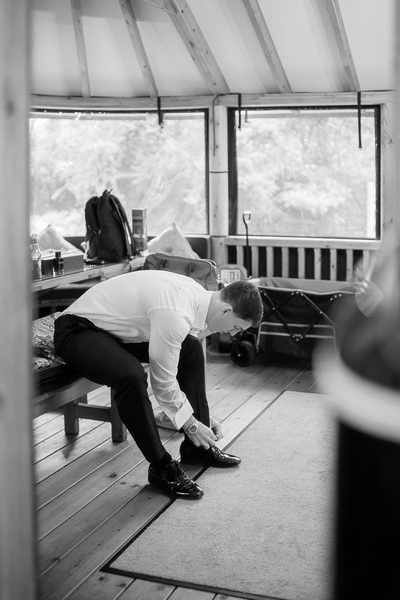 Black and white photo of groomsmen lounging on benches in a bright room.