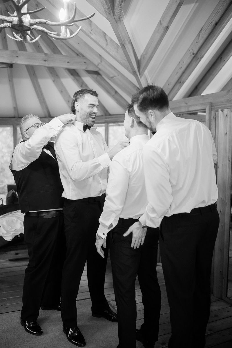 Black and white photo of people in formal attire lined up against a wooden beam ceiling.