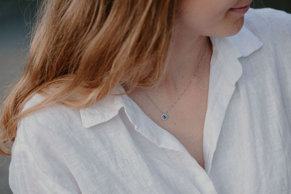 Close-up profile view of a woman in a white blouse with delicate details against a soft light background.