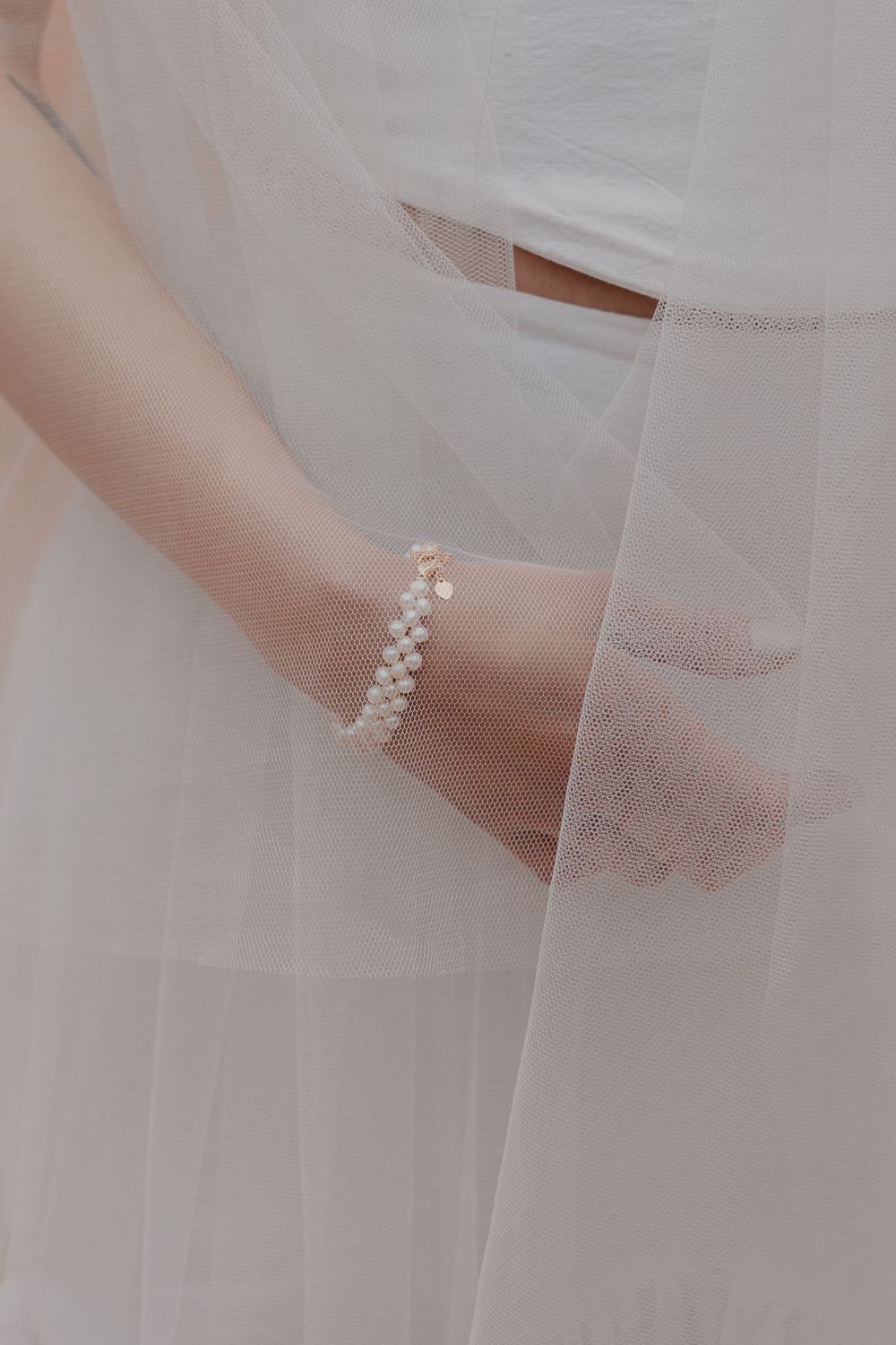 Delicate white tulle fabric with lace details drapes elegantly in a soft, ethereal pattern.