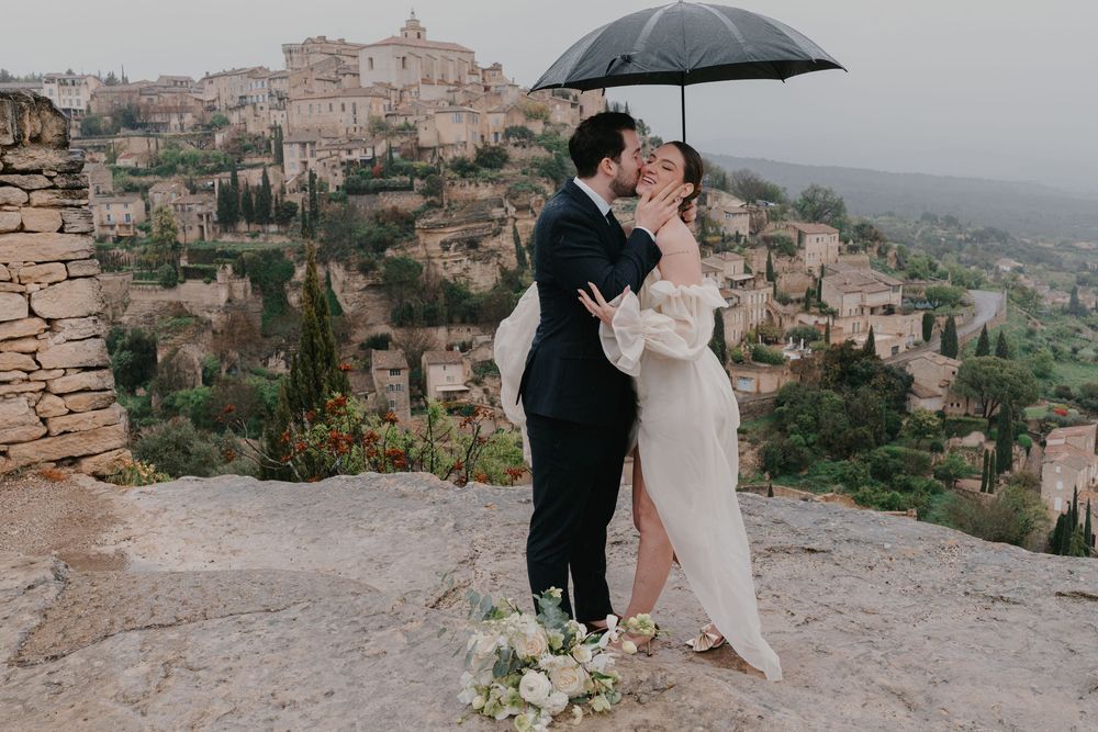 A romantic couple shares tender moments against the scenic backdrop of an Italian hillside town.