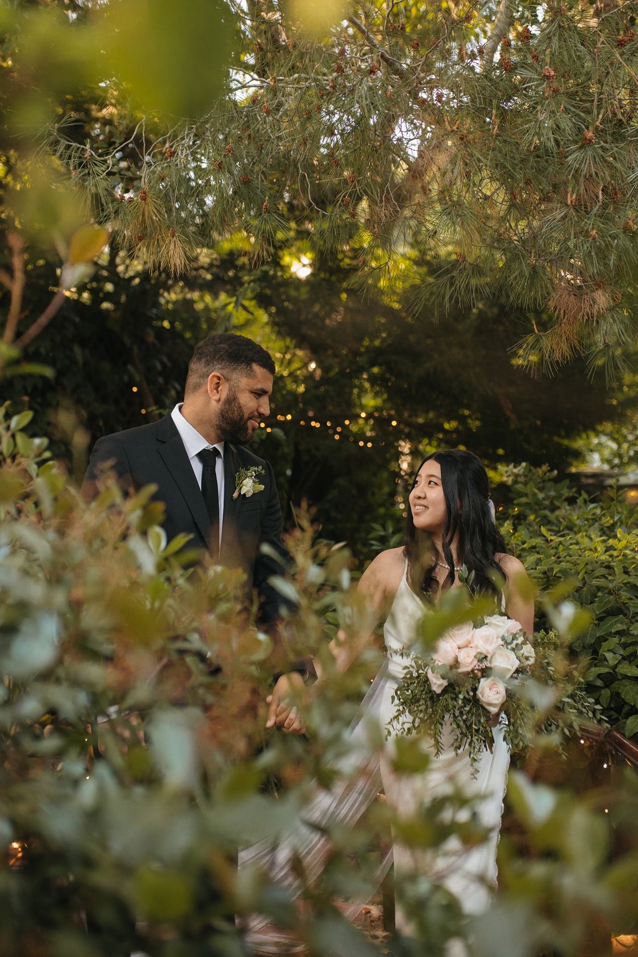 A couple shares a romantic moment in a lush garden setting with soft natural lighting and greenery Inn of the Seventh Ray in Topanga.