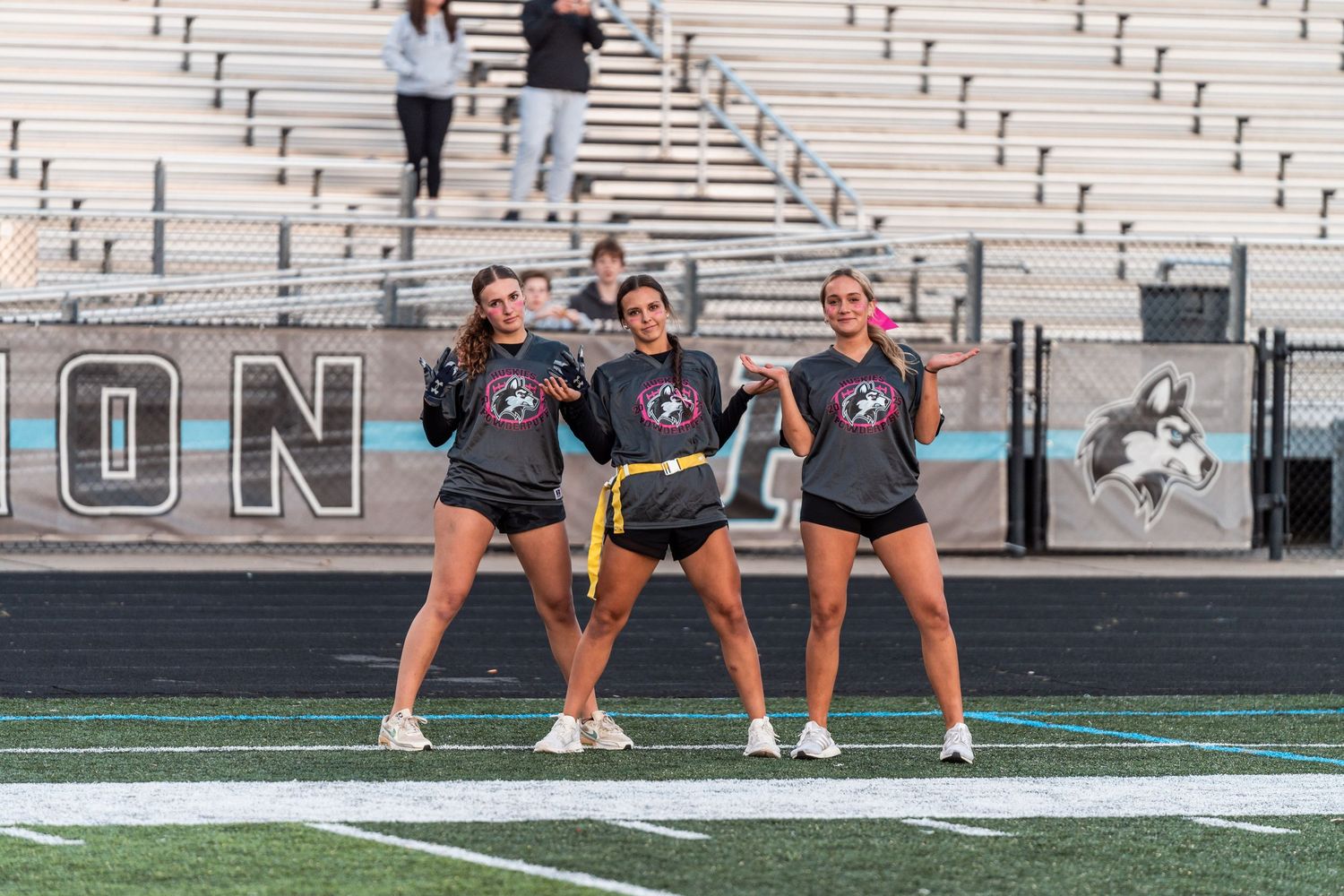 High school cheerleaders perform a coordinated dance routine during a football game performance.