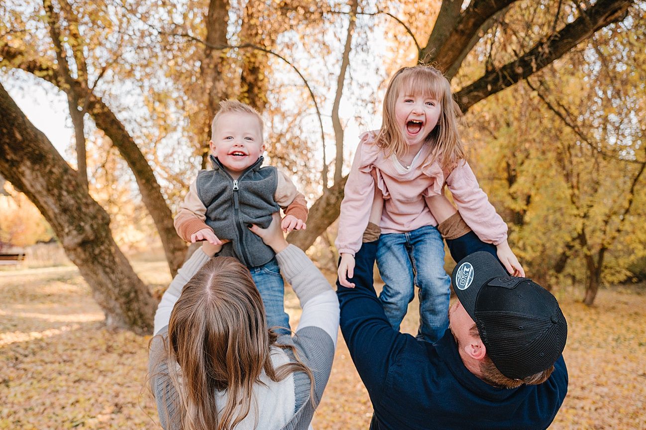A group of people share joyful moments together during an autumn photoshoot in a park with golden leaves.