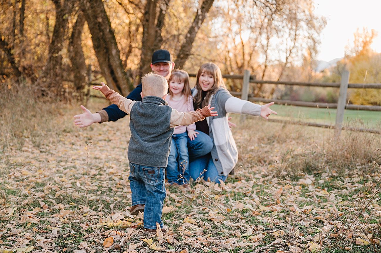 A group enjoys a playful autumn day together in a park filled with fallen leaves during golden hour.