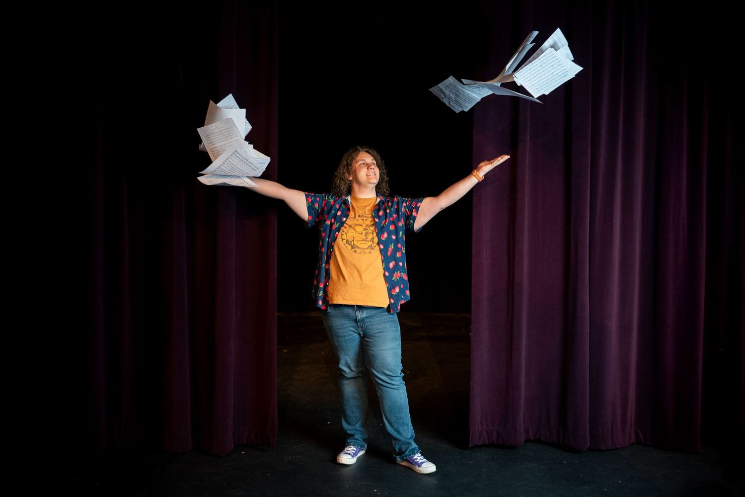 A performer in jeans and yellow shirt strikes dynamic poses against a dark curtain backdrop in six sequential shots.