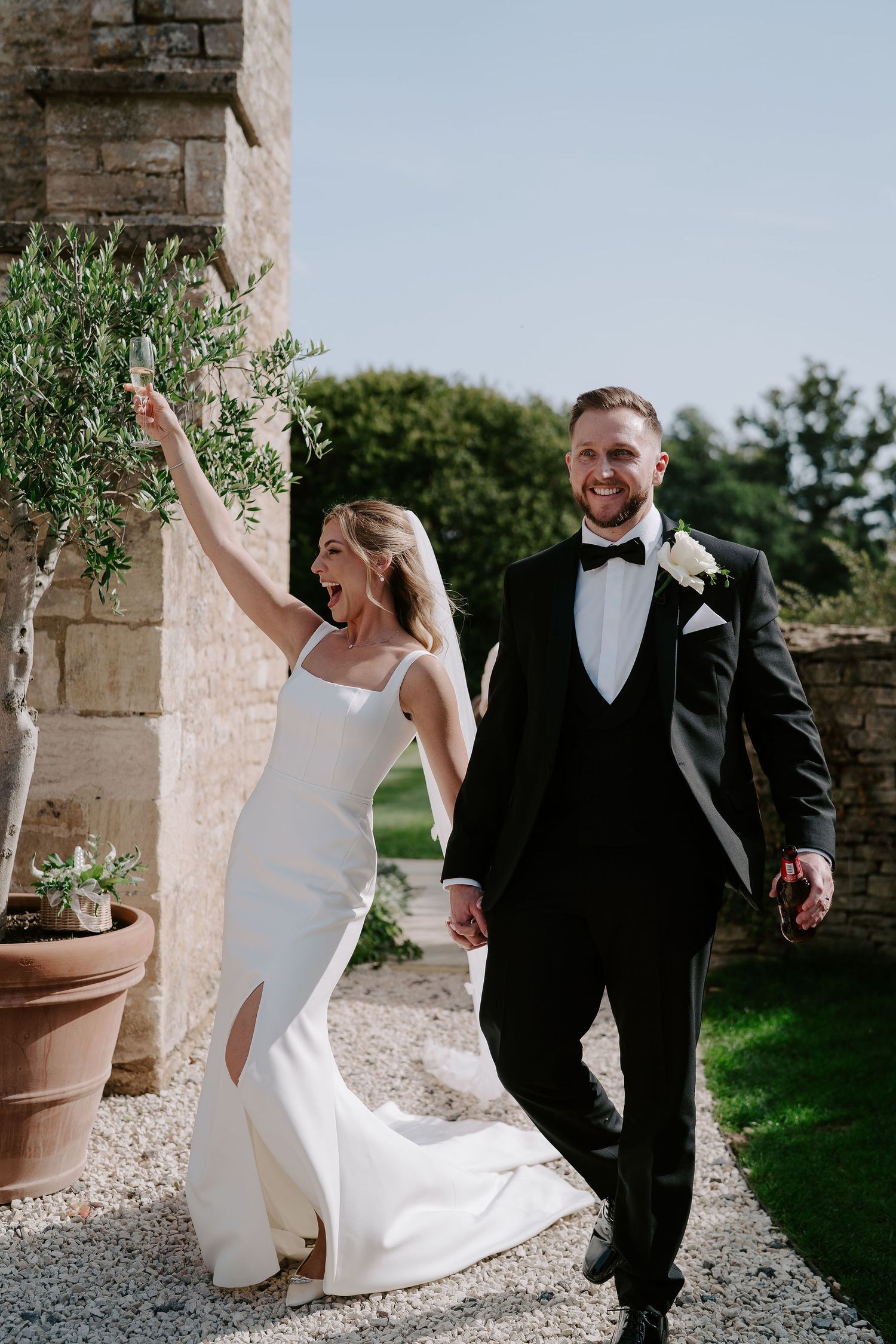 bride and groom smiling and laughing as they enter the drinks reception at ivy lodge in cirencester