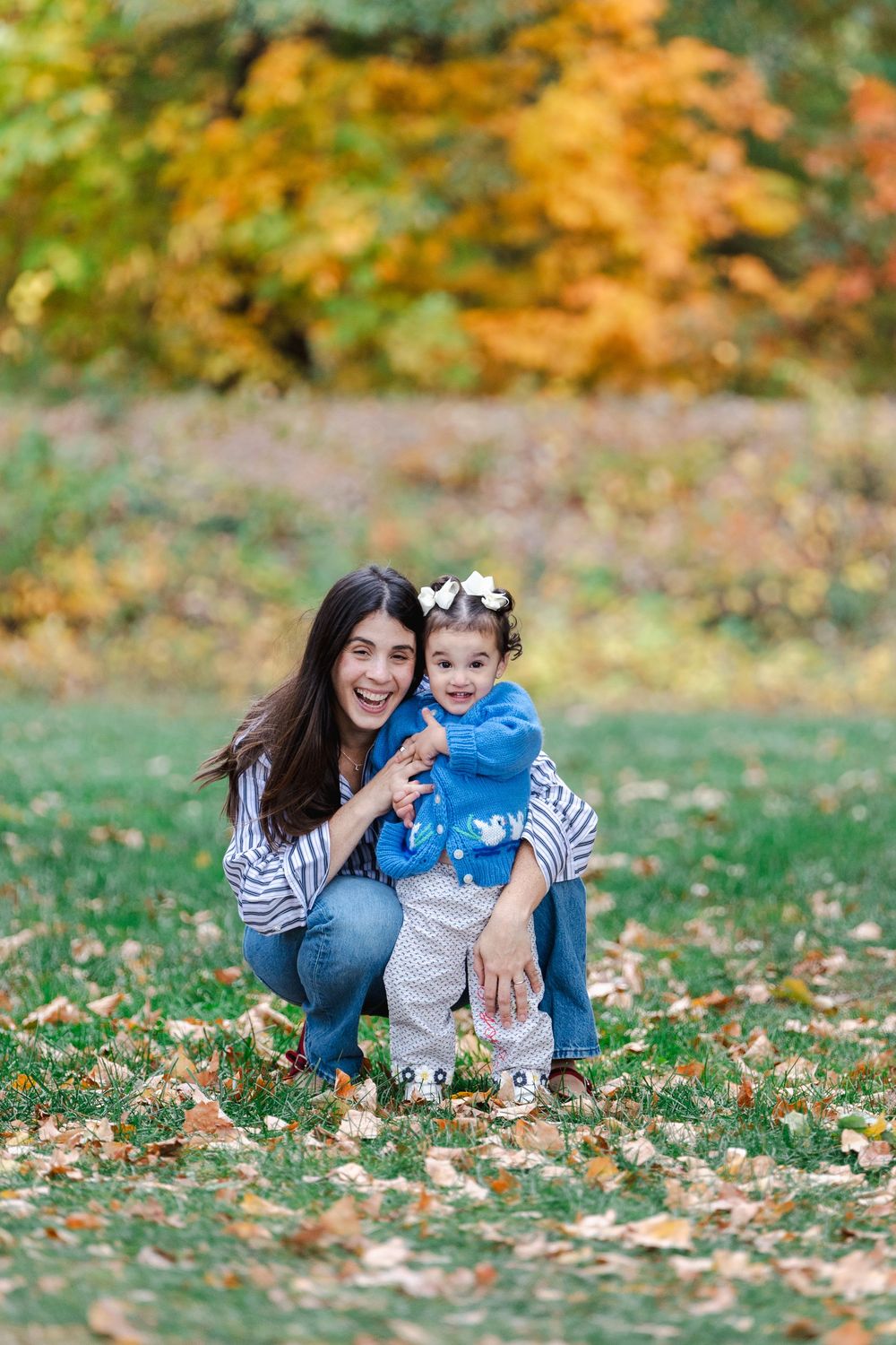 A joyful autumn photoshoot with people playing and laughing together among fallen leaves.