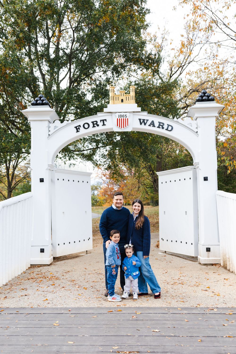 A series of photos showing a family against the white entrance gate of Fort Ward during fall.