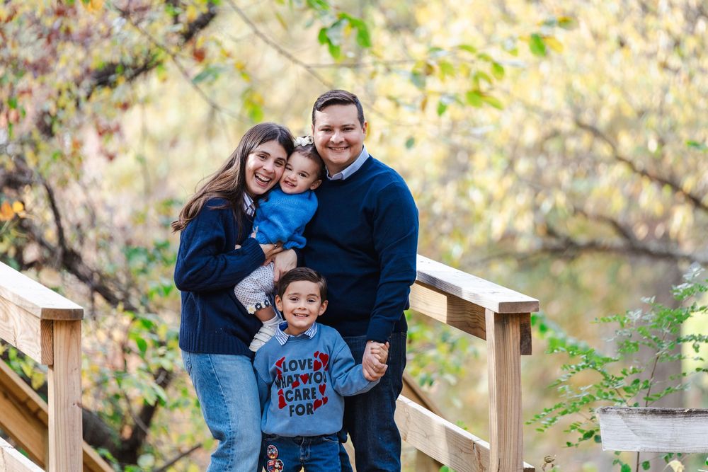 A family wearing coordinated blue outfits poses together outdoors during an autumn photoshoot in nature.