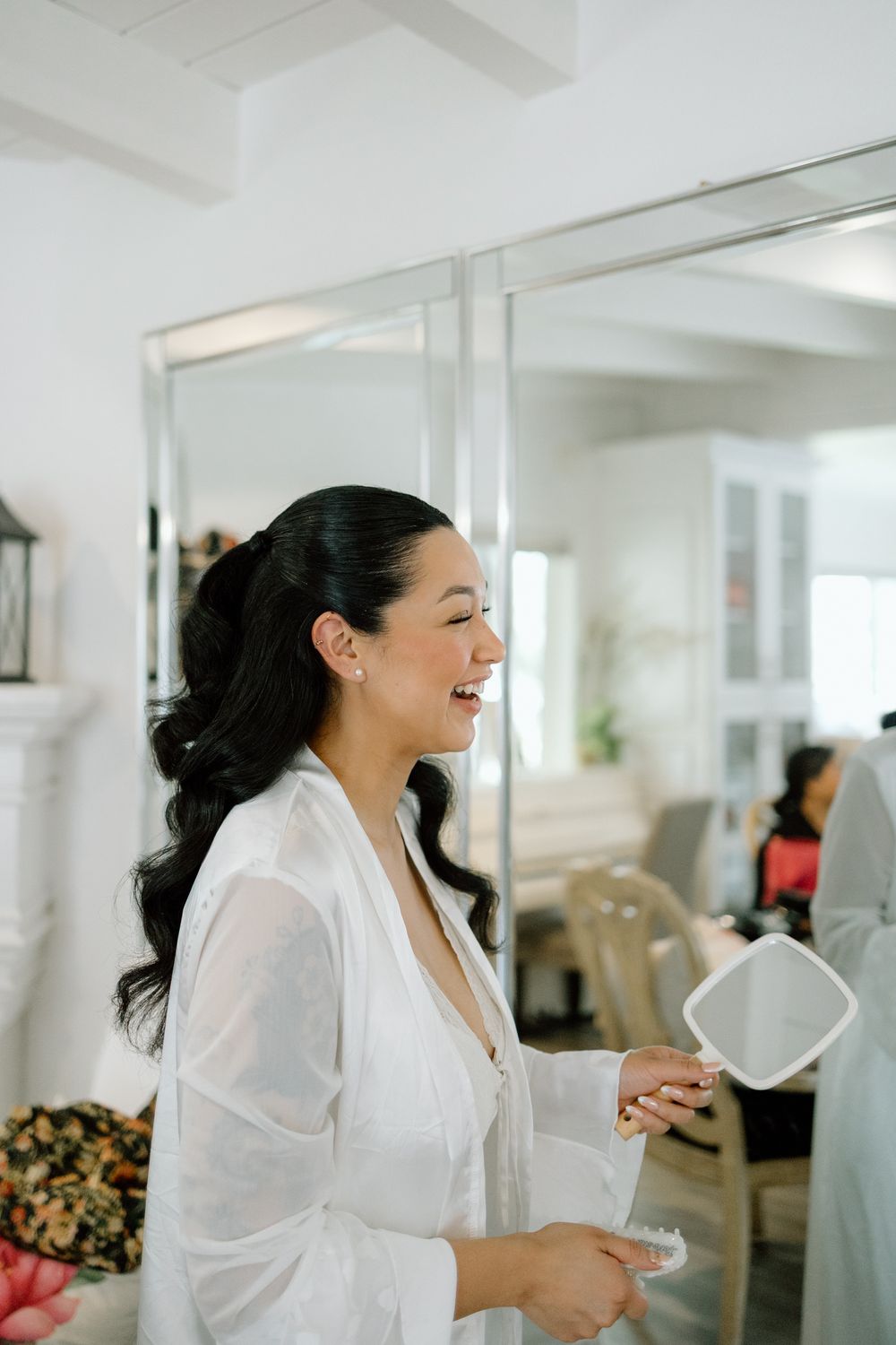 A joyful moment captured during wedding preparation in a bright white room.