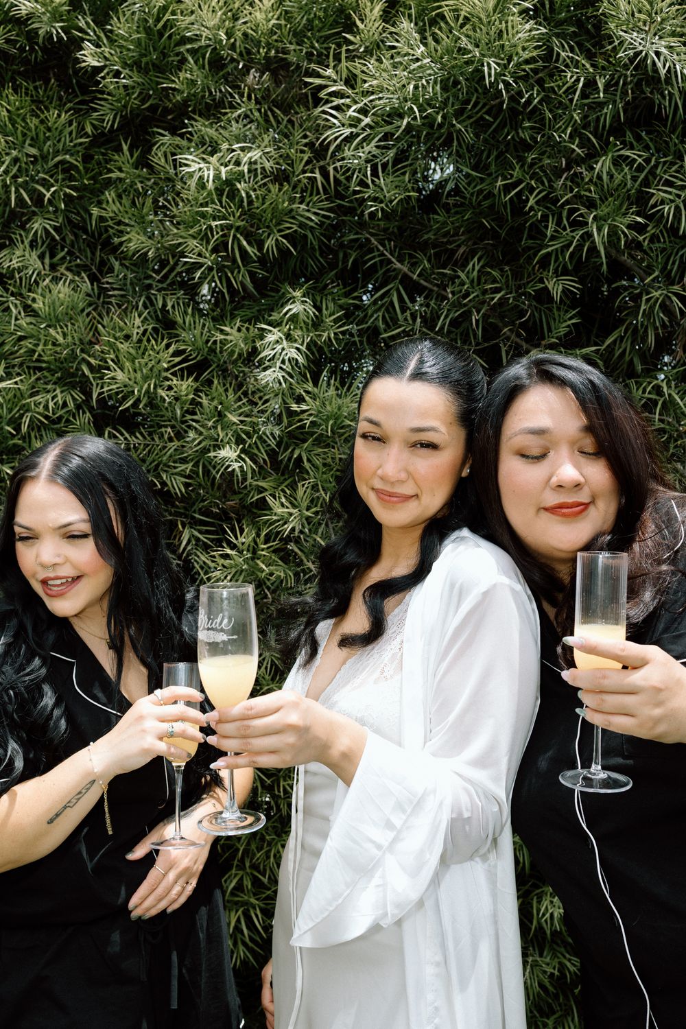 Wedding party members in black and white attire posing with champagne glasses.