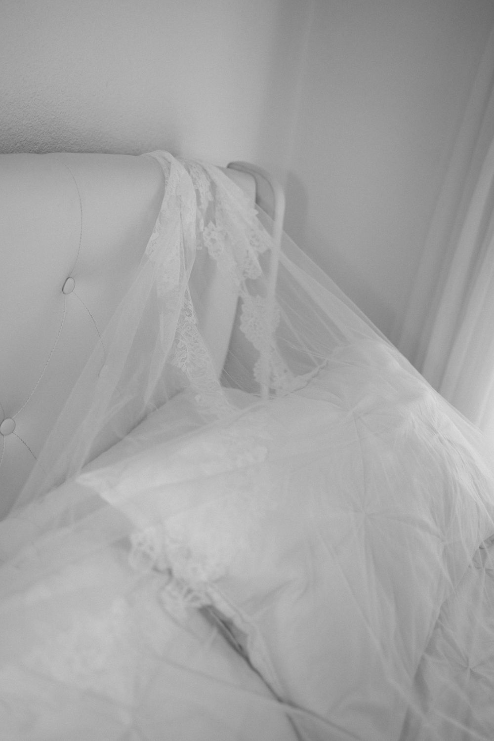 Ethereal white tulle fabric draped over bed in soft black and white tones.