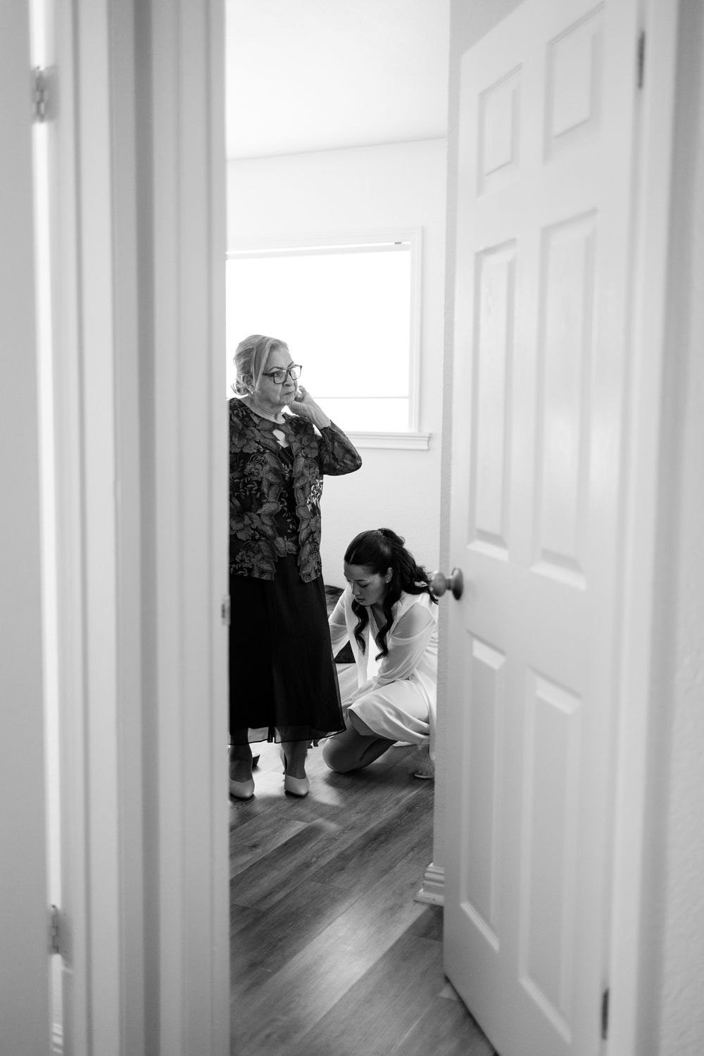 Black and white photo showing preparation scene through partially open doorway.