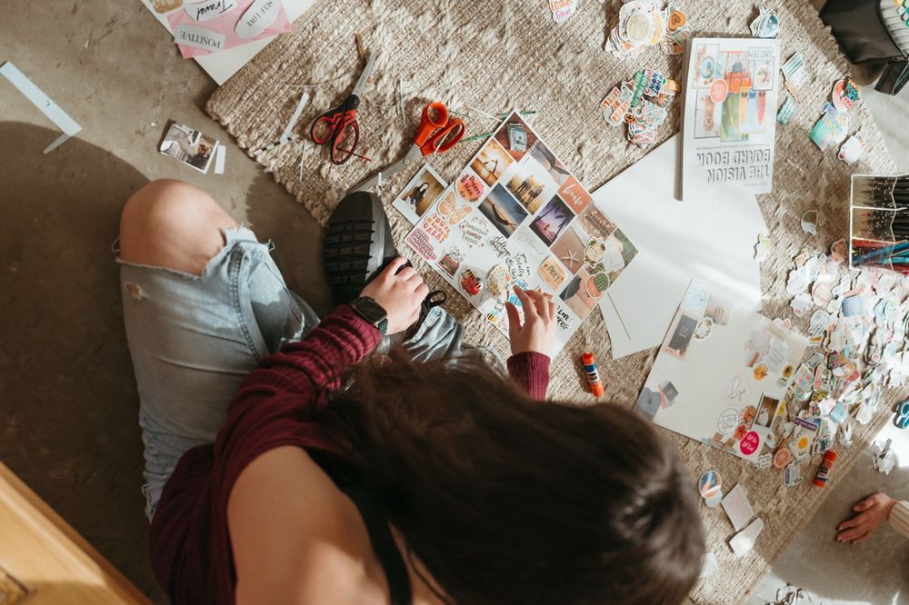 Overhead view of someone arranging photos and cards on a textured surface.
