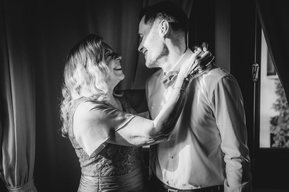 Madre abrazando al novio durante los preparativos, momento emotivo antes de la boda en blanco y negro.