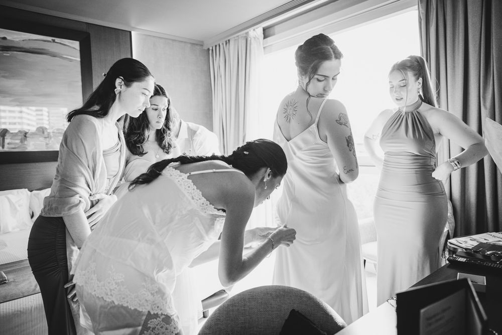 Novia rodeada de amigas mientras se viste momentos antes de la boda