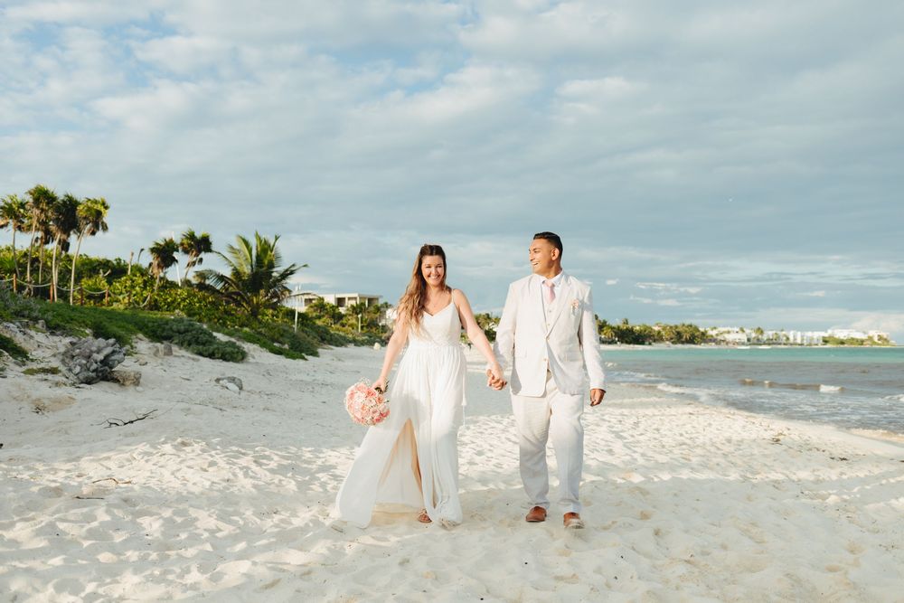 brideandgroom-pinkbouquet-pinkroses-weddingdress-beachwedding-palmtree-blueocean-whitesand-destinationwedding-bahiaprincipeluxuryakumal