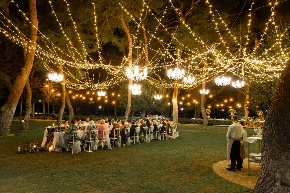Wedding party enjoys lavish banquet in evening under thousands of lights and chandeliers at Italian destination wedding