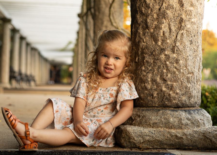little girl making a silly face leaning against a column