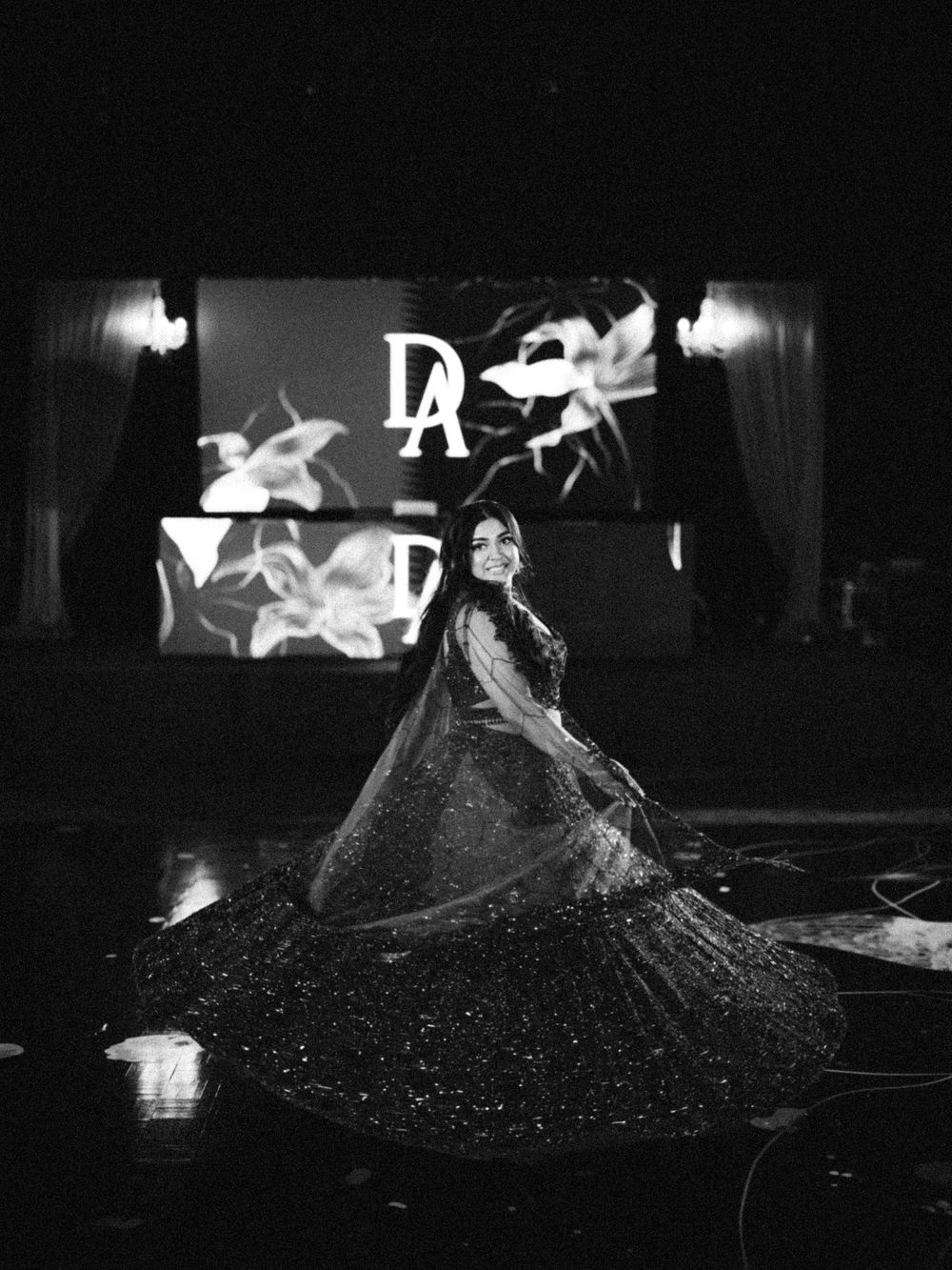 A dramatic black and white performance art piece featuring a flowing dress with glittering particles in motion.