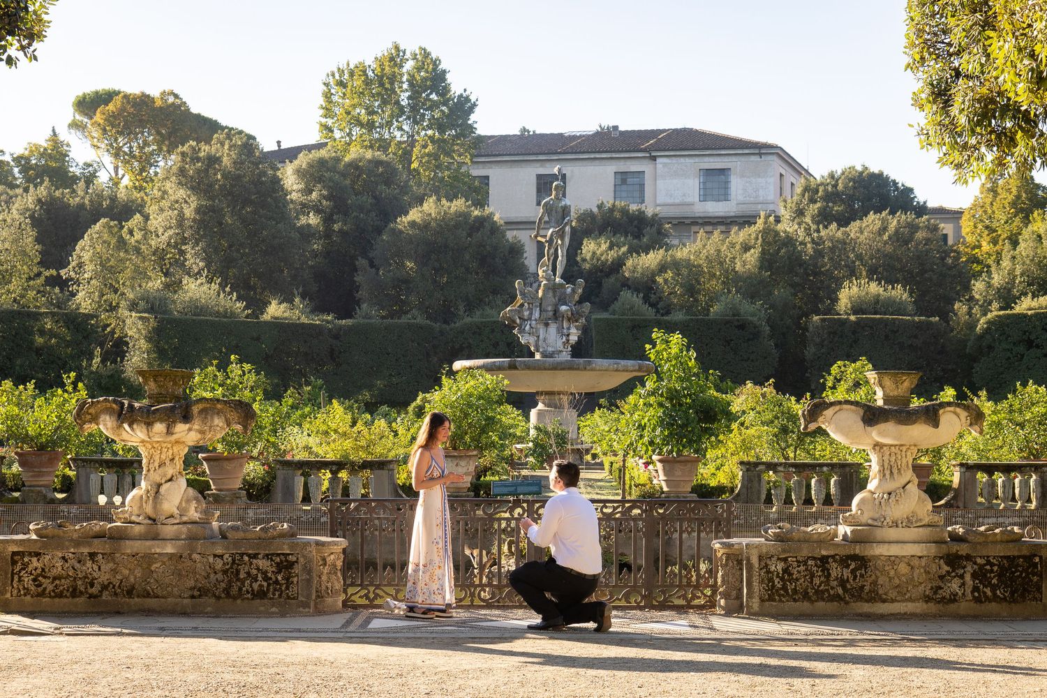 A panoramic view of a stone terrace with lush greenery and elegant architecture in a Mediterranean setting.