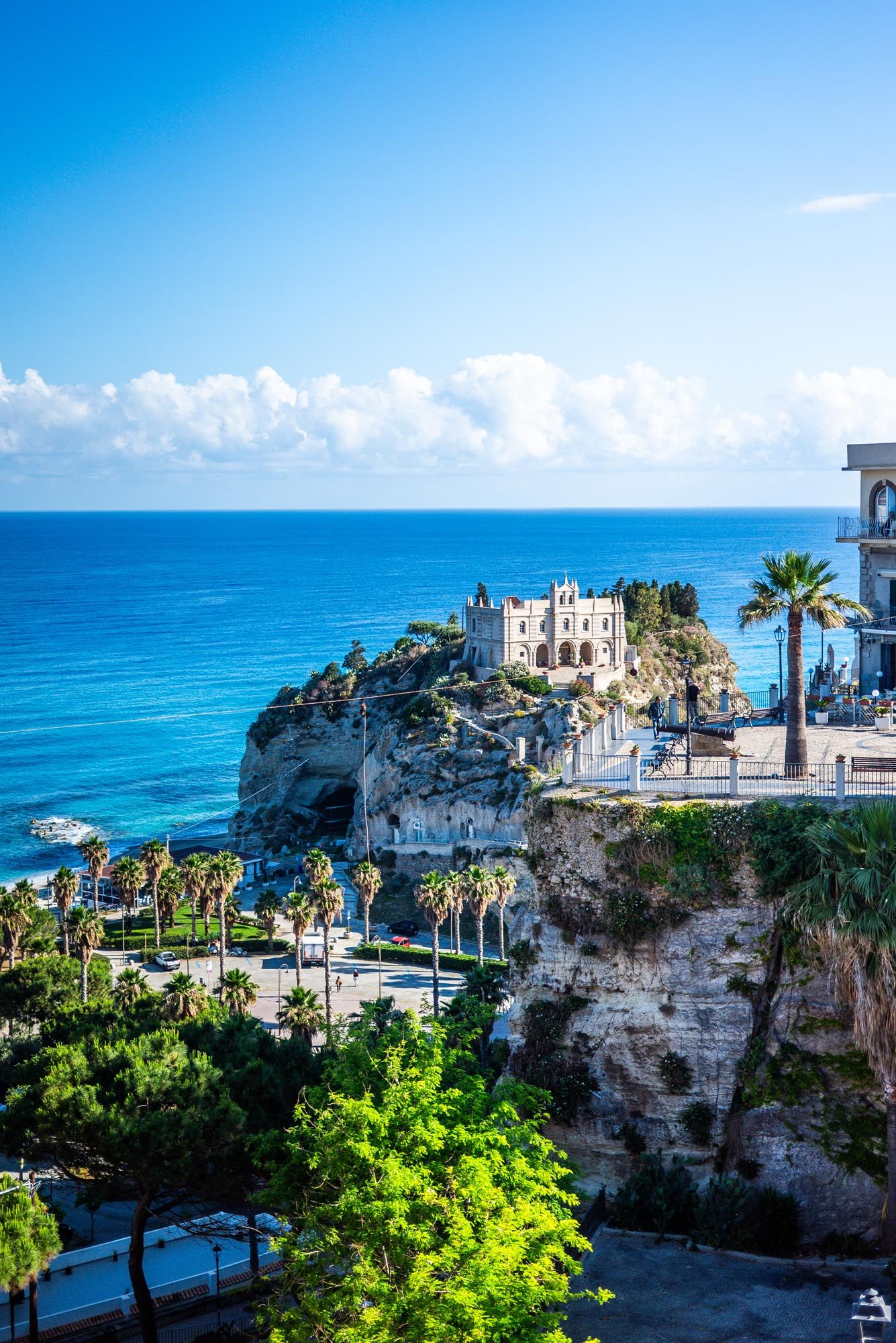 Scenic coastal view of white buildings perched on limestone cliffs overlooking turquoise Mediterranean waters in Italy.